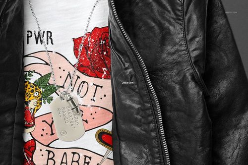 Close-up front view of a kids t-shirt mockup with a bold graphic design, under a black leather jacket and necklace.