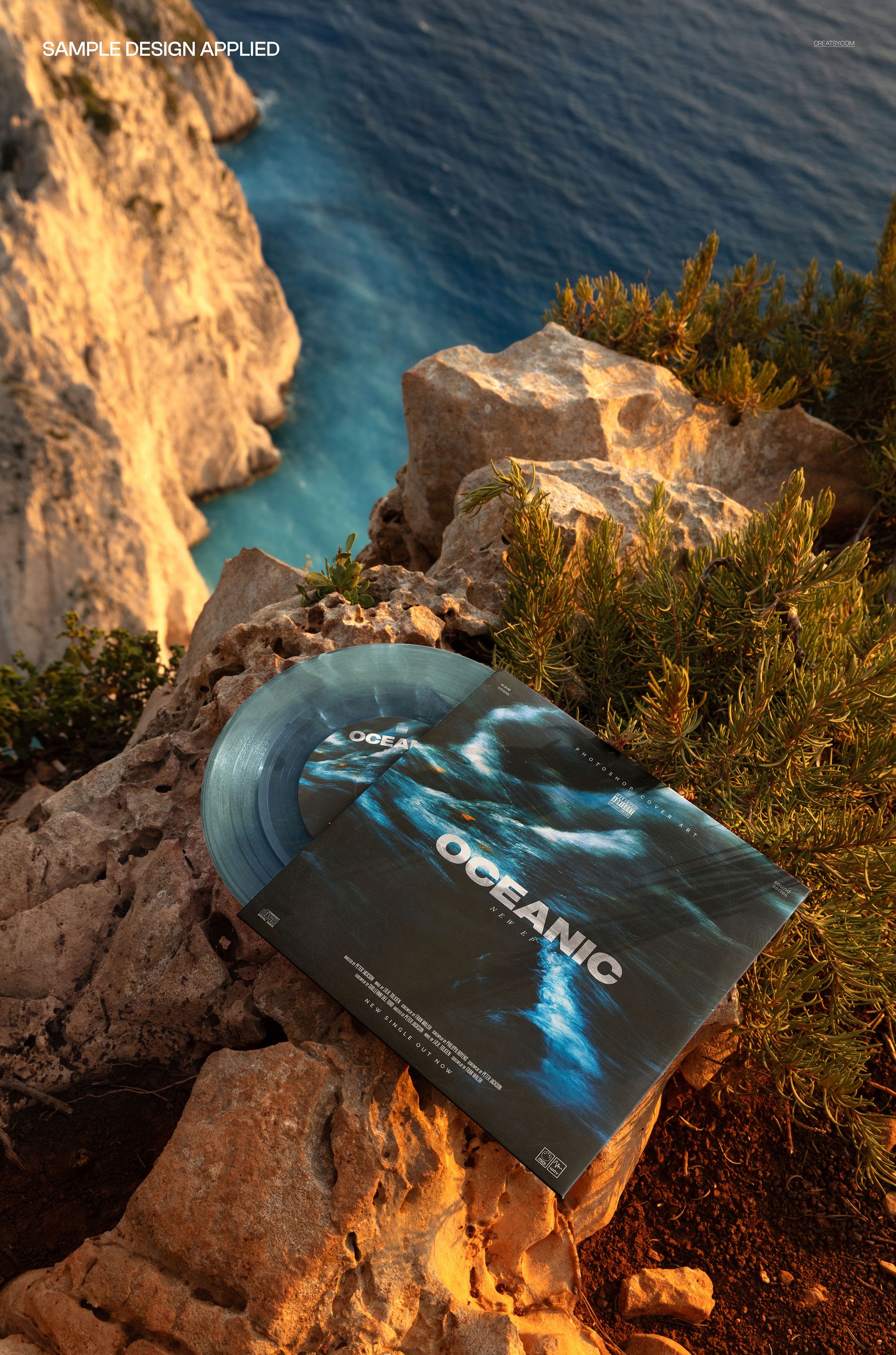 Translucent vinyl record and matching album cover mockup set on rocky outdoor cliff with ocean in the background.