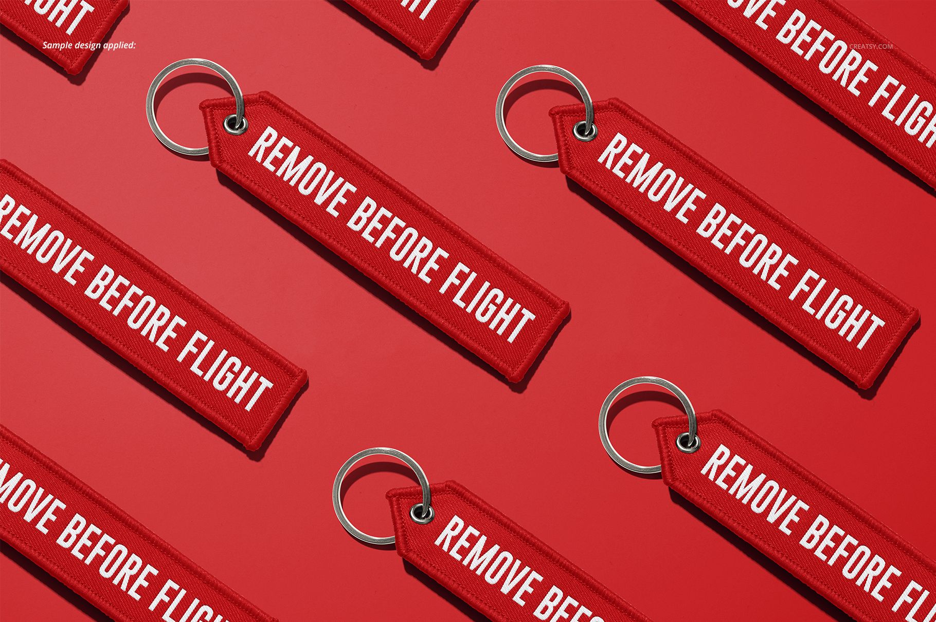 PSD mockup set showing several 'Remove Before Flight' keychains with metal loops, positioned on a vibrant red backdrop.