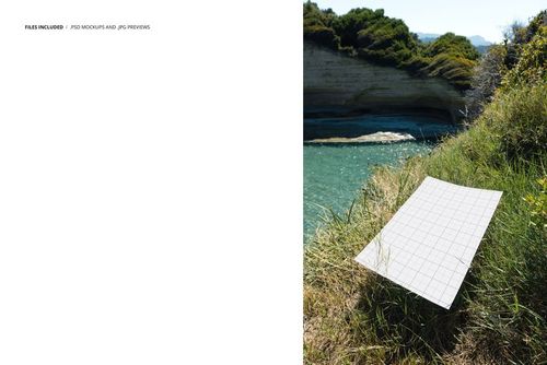 Rectangular poster mockup with grid pattern displayed on grassy hillside overlooking turquoise water and rocky cliffs.