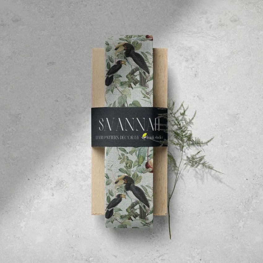 Wide cotton ribbon mockup featuring a botanical and bird pattern, wrapped around a wooden block with a black label on a textured surface.