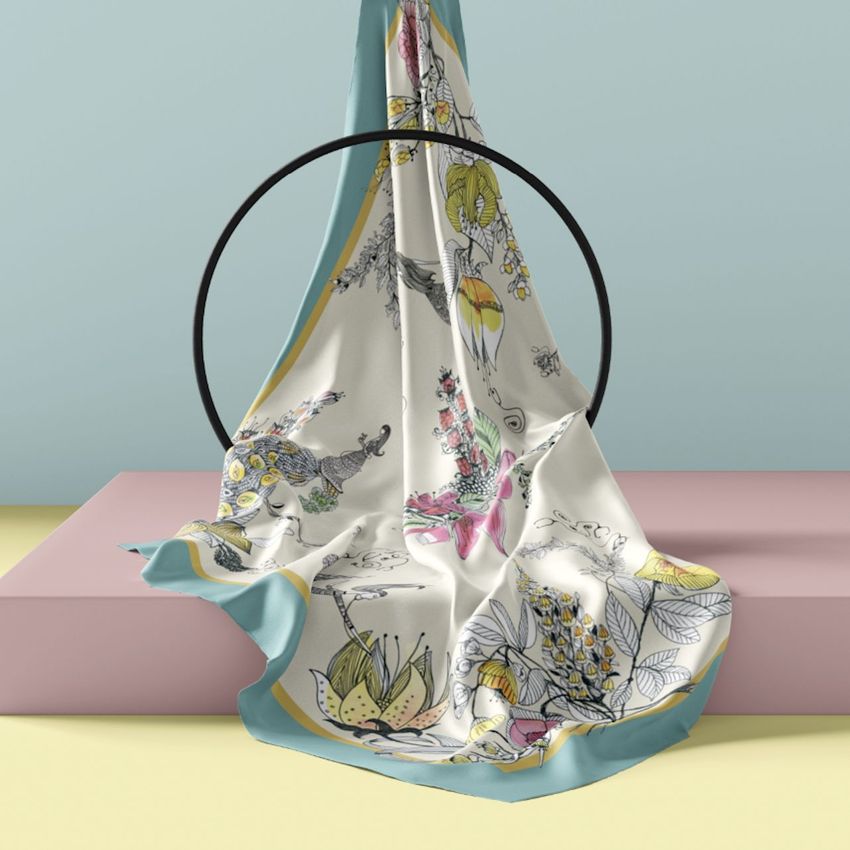Silk scarf mockup draped over a black circular stand, featuring abstract floral patterns in pastel colors on a soft background.