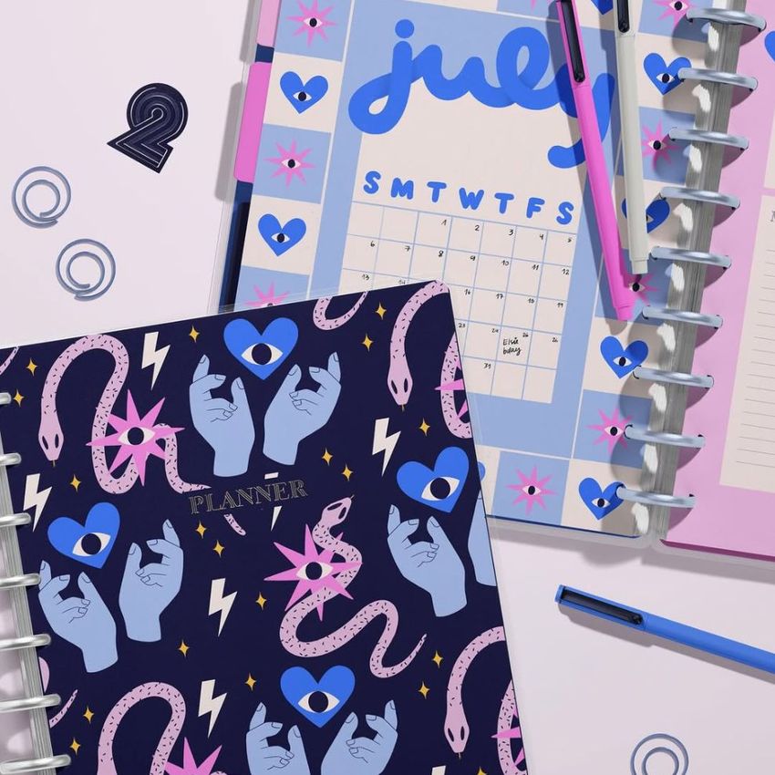 Colorful planner mockup with graphic designs, open to a calendar page and notes section, with pens and decorative cutouts on a light surface.