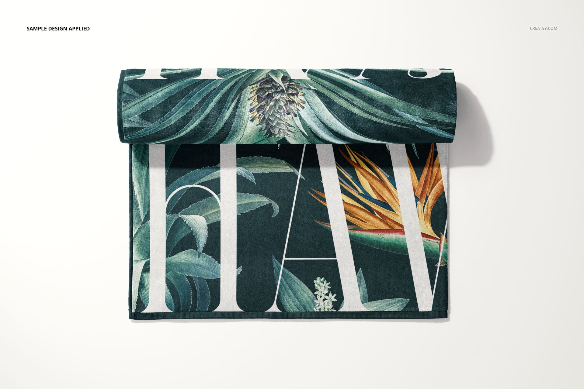 Beach towel mockup featuring a botanical pattern with large leaves and flowers, displayed folded on a light surface.