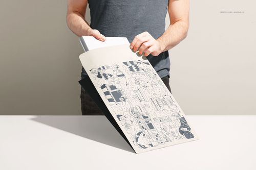 Front view of a kraft mailer mockup with blue line art design, person placing white envelope inside on desk.