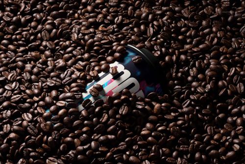 PSD mockup featuring a paper cup with a black lid surrounded by glossy coffee beans, close-up perspective.