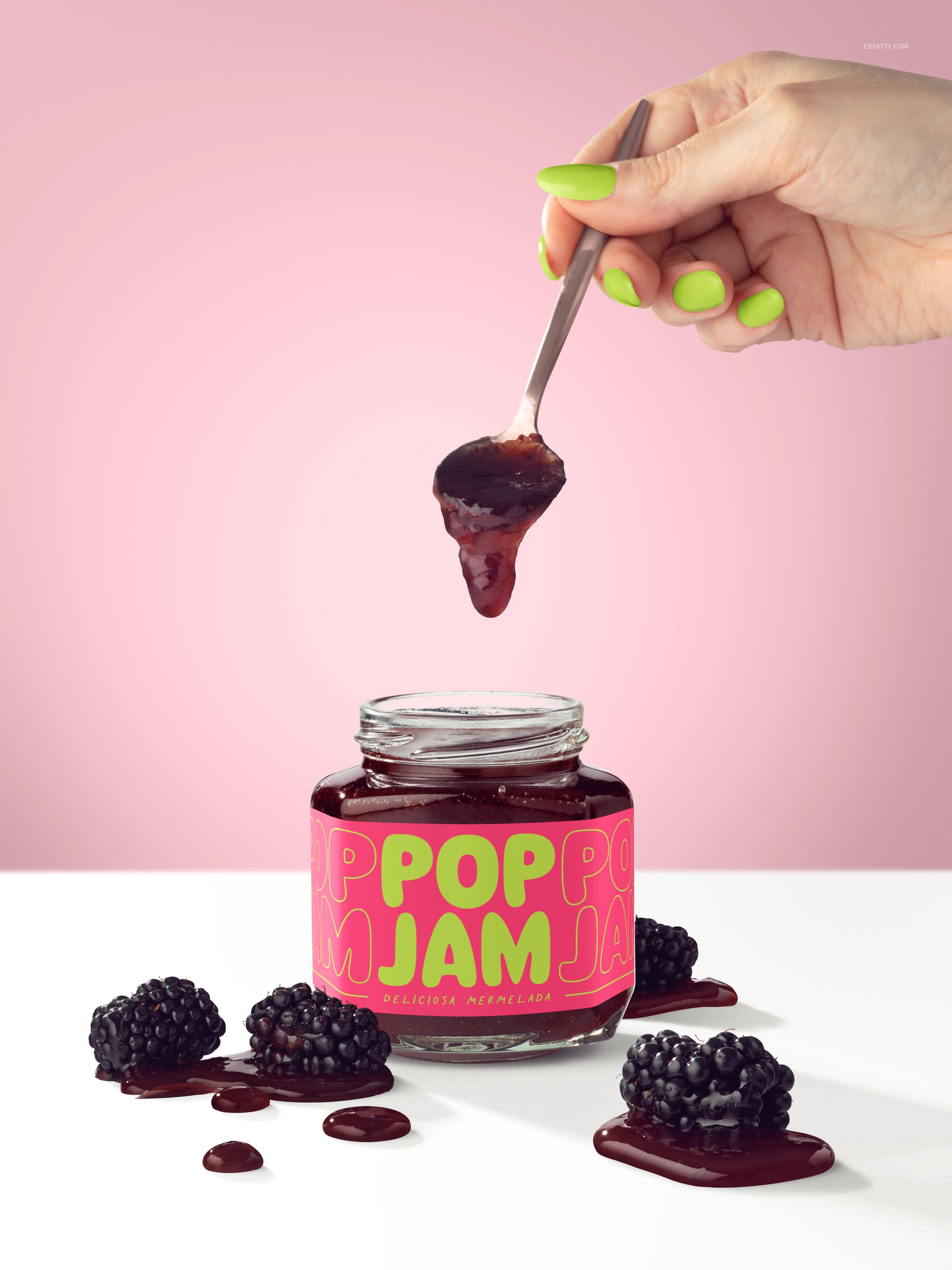 Close-up of a blackberry jam jar mockup with vibrant label, jam on a spoon, and fresh blackberries on a white surface.