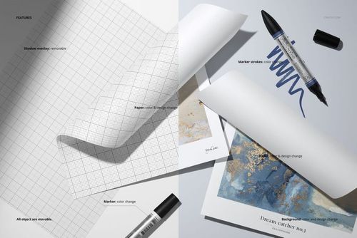 Top view of two folded sheets of paper mockup with grid and artwork designs, surrounded by black markers on a light surface.