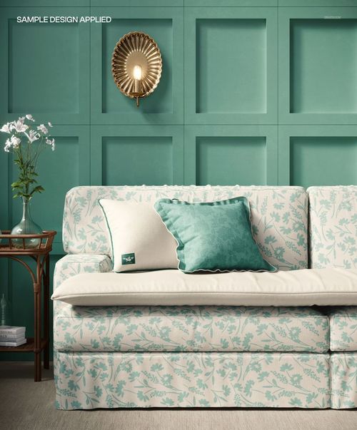 PSD mockup showing an upholstered sofa with botanical prints, teal cushion, and elegant wall sconce in a modern interior.