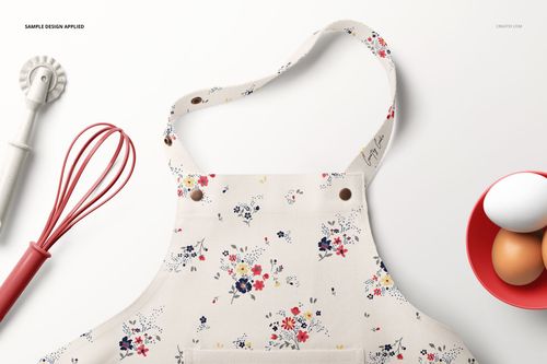 Kids apron with a floral pattern displayed in a top view mockup, surrounded by baking tools and a bowl of eggs.
