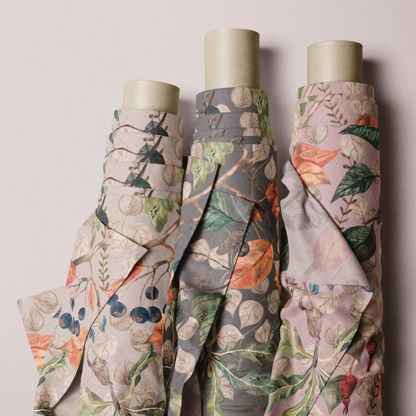 Three fabric rolls mockup featuring autumn-inspired botanical patterns in muted tones, arranged upright against a light background.