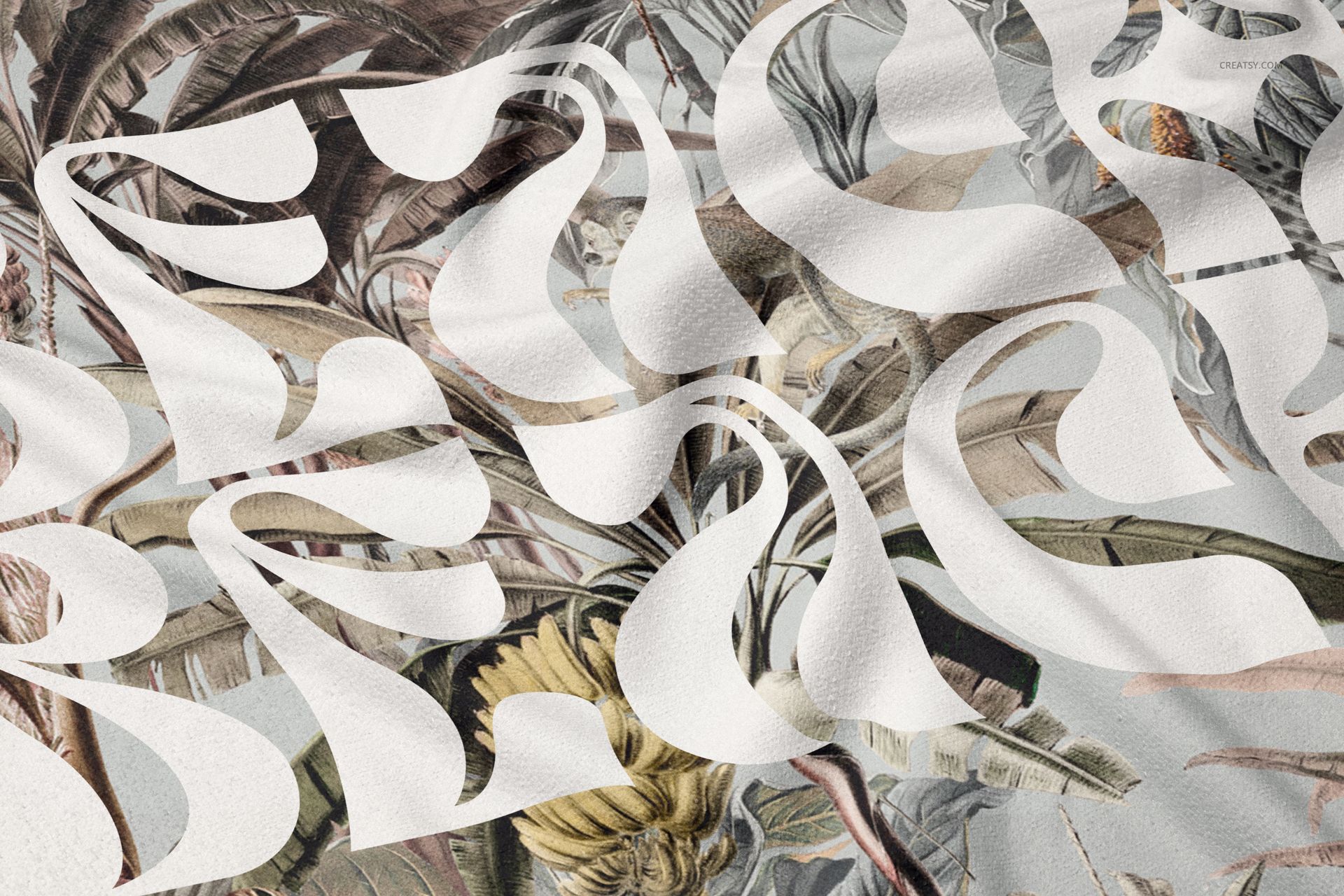 Fringed beach towel mockup with abstract white lettering over a botanical pattern, shown in a close-up view.