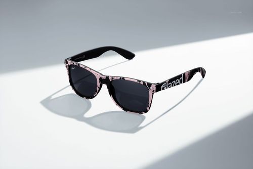 PSD mockup of custom printed sunglasses featuring dark lenses and a pink and black patterned frame, angled view.
