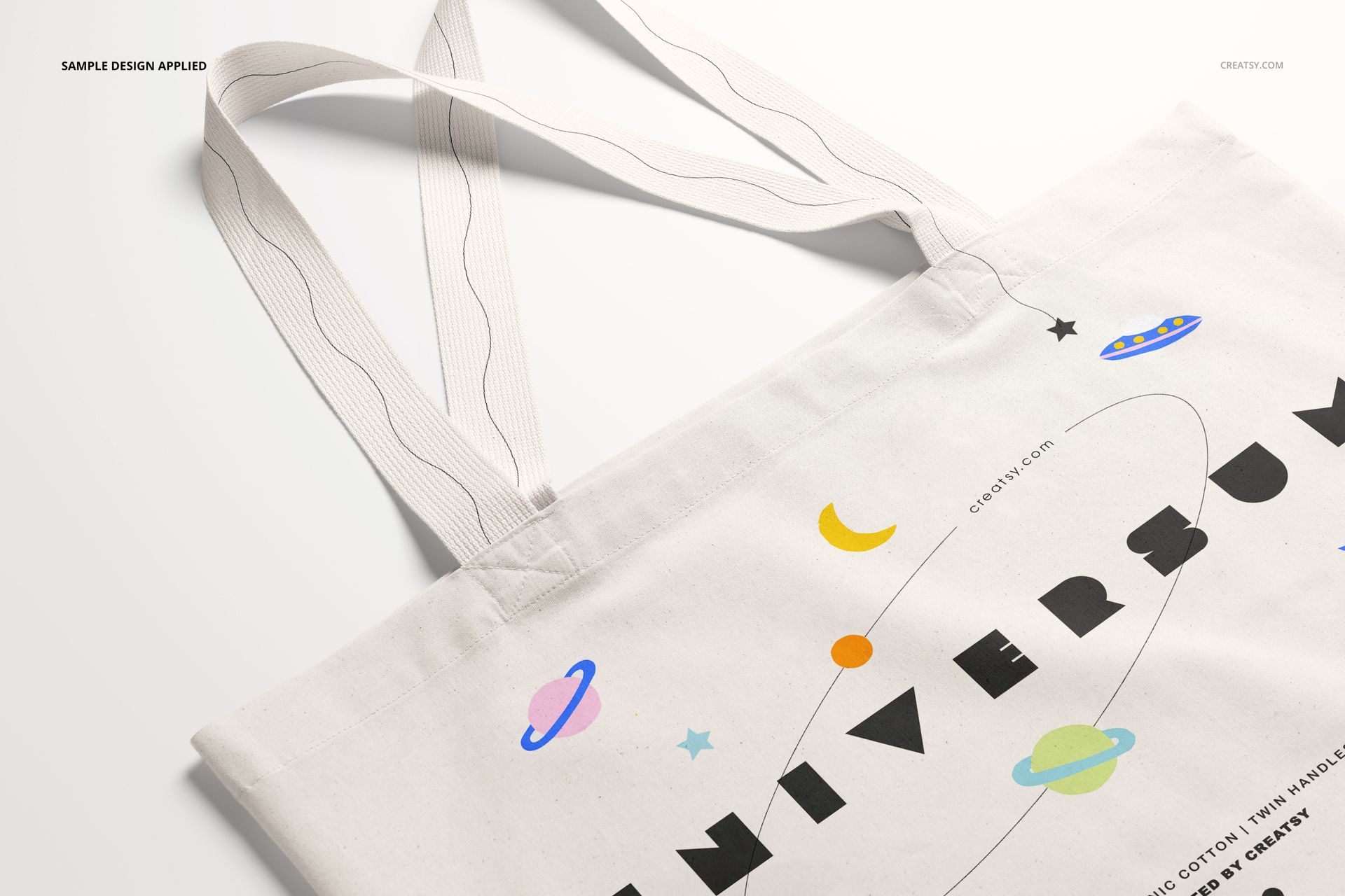 Front angled view of a weekender tote bag mockup with long handles, featuring a space-themed design on light fabric.