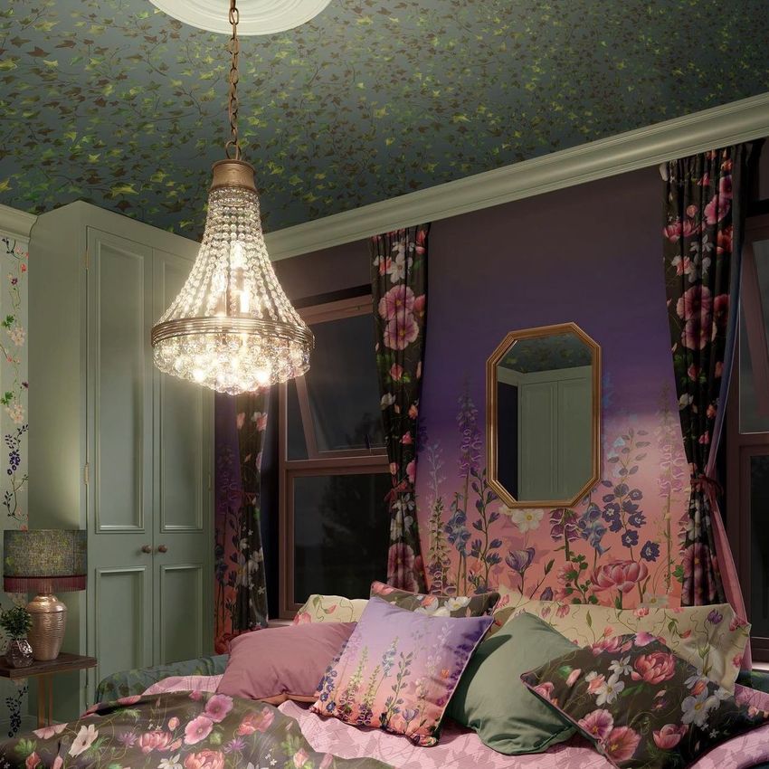 Luxury bedroom mockup featuring floral wallpaper and bedding, a crystal chandelier, and pastel green cabinets at night.
