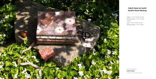 PSD mockup showing folded fabric with pink and white flower patterns on a rock, set in a leafy garden scene.