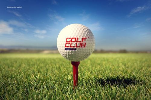 Golf ball mockup standing on a red tee in lush grass, with clear blue sky and soft sunlight in the background.