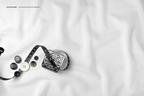 Top view close-up of white fabric with measuring tape, assorted buttons, and subtle folds, shown in a mockup scene.
