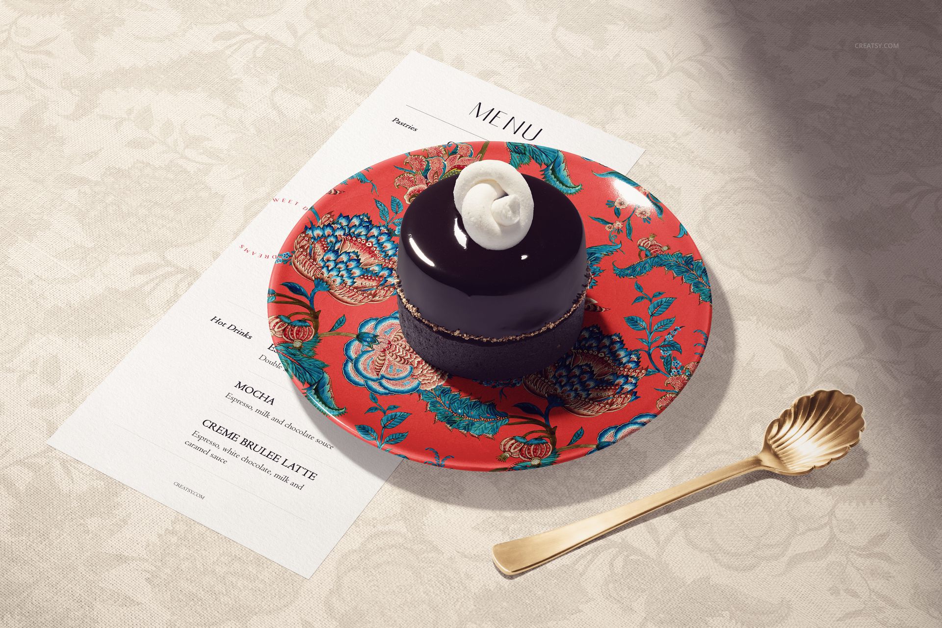 Round ceramic plate with vibrant red floral pattern, holding a glossy chocolate dessert, viewed from above.