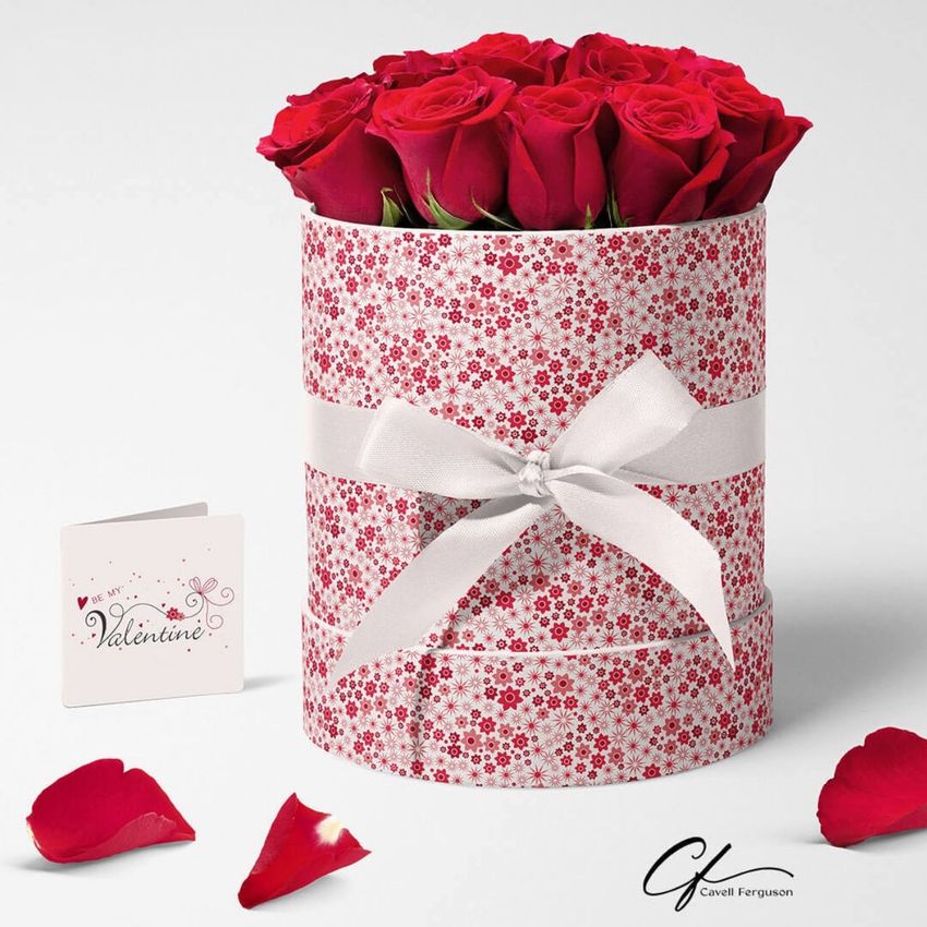 Floral box mockup featuring a round container with a red and white floral pattern, filled with red roses and tied with a white ribbon.