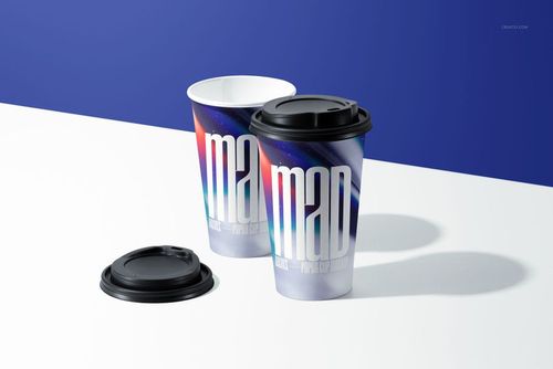 Paper cup PSD mockup set showing two cups with artistic multicolor patterns and black plastic lids on a table.