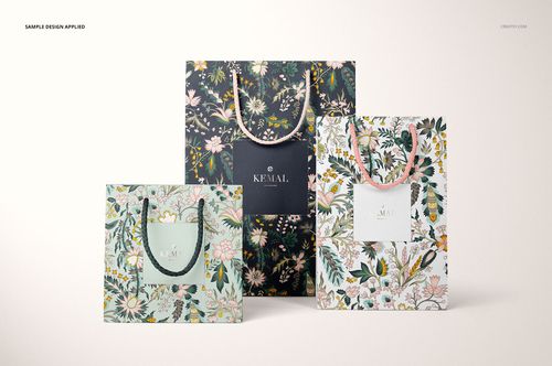 PSD mockup showing three upright paper bags with botanical designs and rope handles, arranged against a pale backdrop.