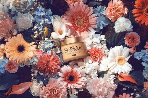 PSD mockup of a cosmetics container placed among vibrant floral arrangements viewed from above.