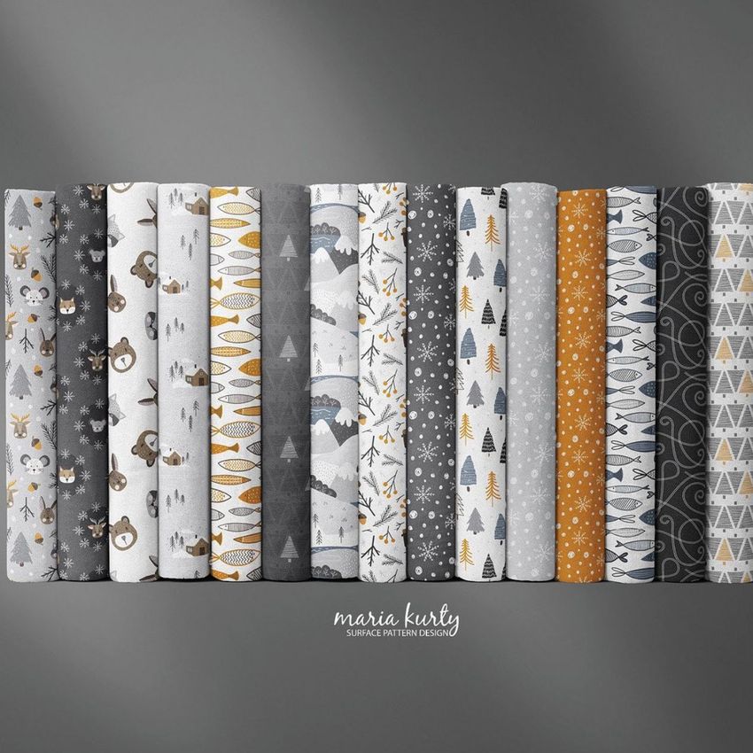 Folded fabrics mockup featuring twelve fabric rolls with winter woodland patterns in gray, white, and mustard tones on a gray background.