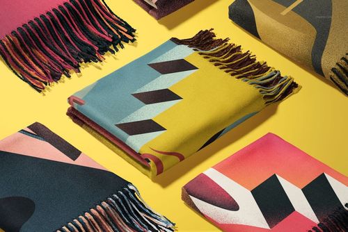 PSD mockup of multiple tassel fringe blankets with vibrant patterns, viewed from above against a yellow backdrop.