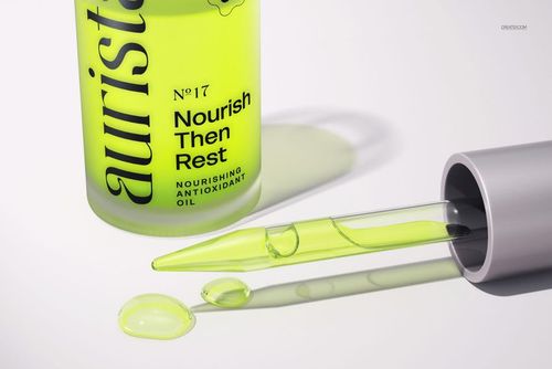 PSD mockup showing a cosmetic dropper bottle with vivid yellow liquid, glass pipette, and drops beside the bottle.