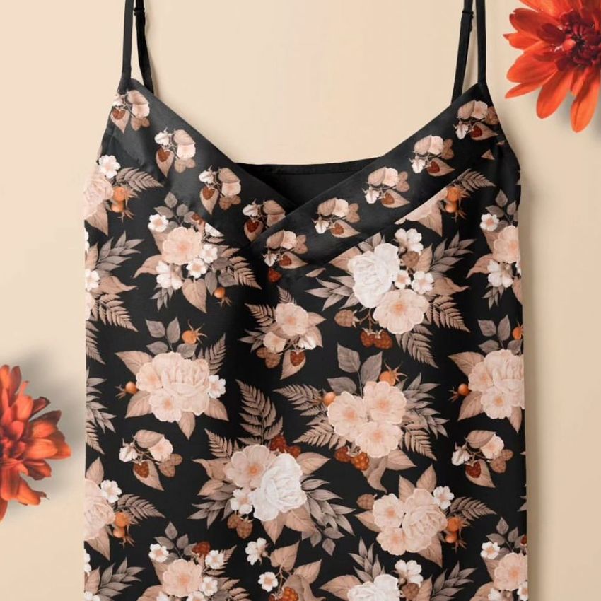 Short silk pajama mockup featuring a black camisole with a beige and white floral pattern, displayed on a neutral background with red flowers.