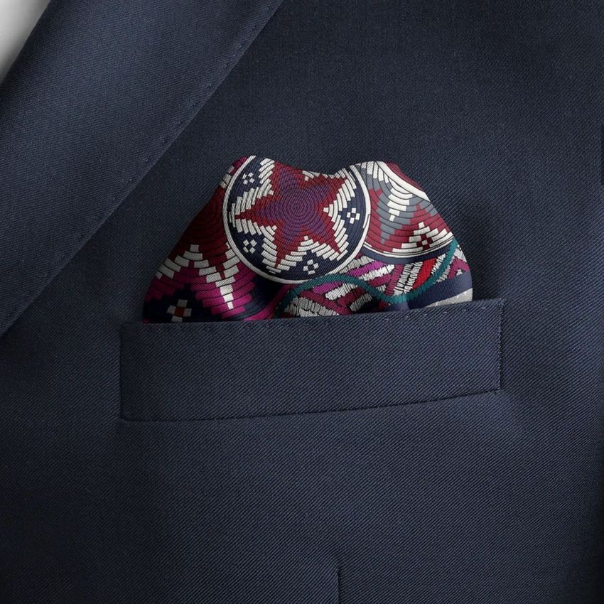 Pocket square mockup featuring a folded, patterned fabric with red, white, and purple geometric designs in a navy suit pocket.