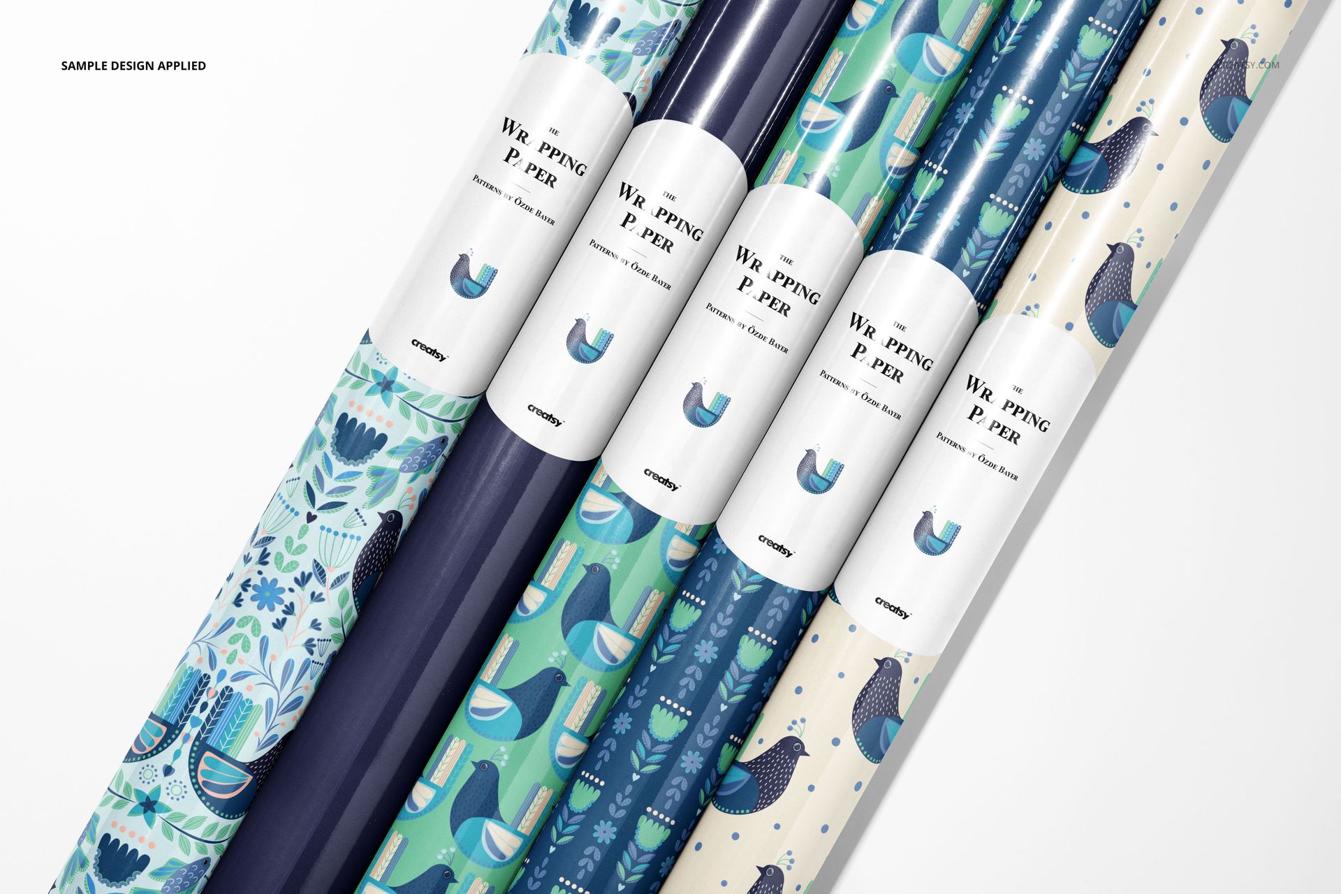 PSD mockup of wrapping paper rolls with colorful bird and plant patterns, arranged side by side in a flat lay.
