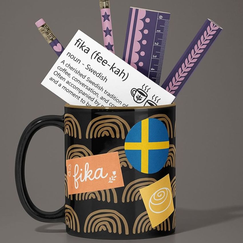Mug mockup with a black cup decorated with colorful stickers, filled with purple pencils, a ruler, and a card with text.