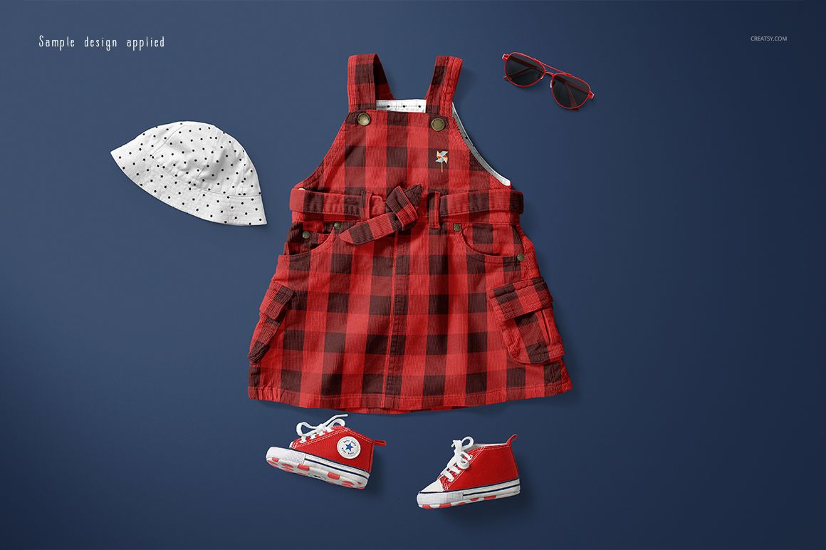 Front view of a baby dress mockup set featuring a red plaid dress, white polka dot hat, red sneakers, and sunglasses on a blue background.