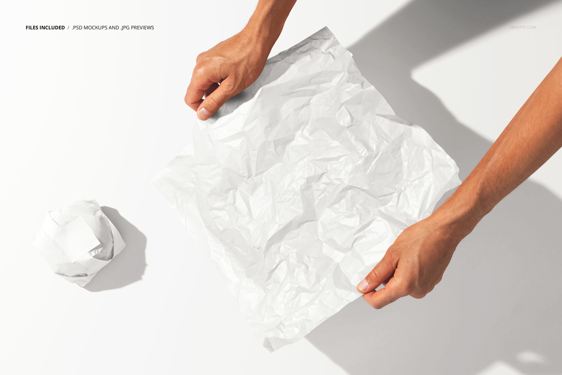 Burger wrapping paper PSD mockup showing hands handling a textured white sheet with a scrunched paper ball beside it.