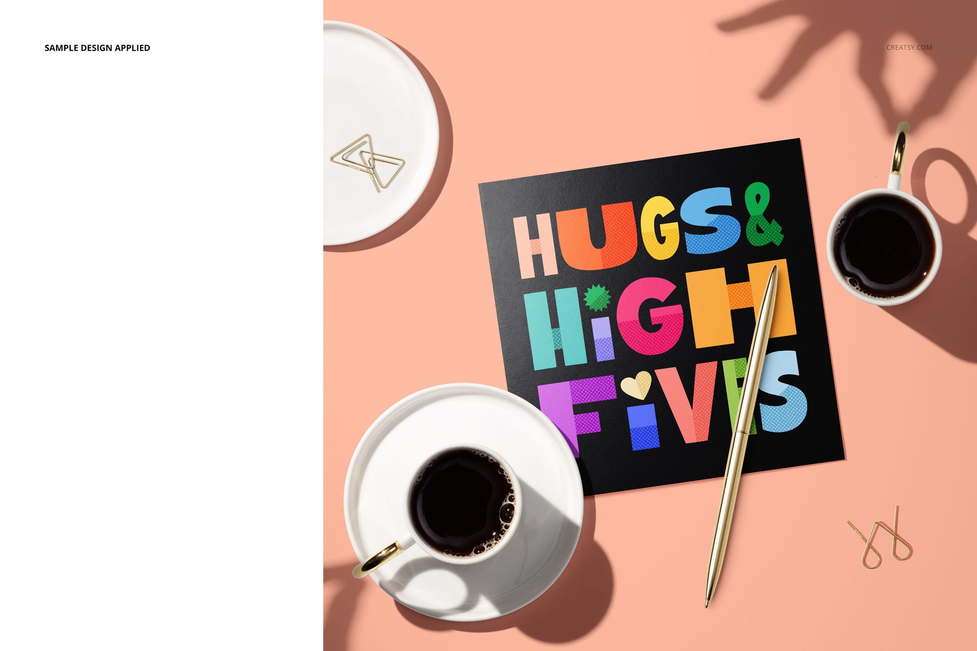 PSD mockup of a square folded greeting card featuring bold multicolored lettering, placed near coffee cups and a pen.