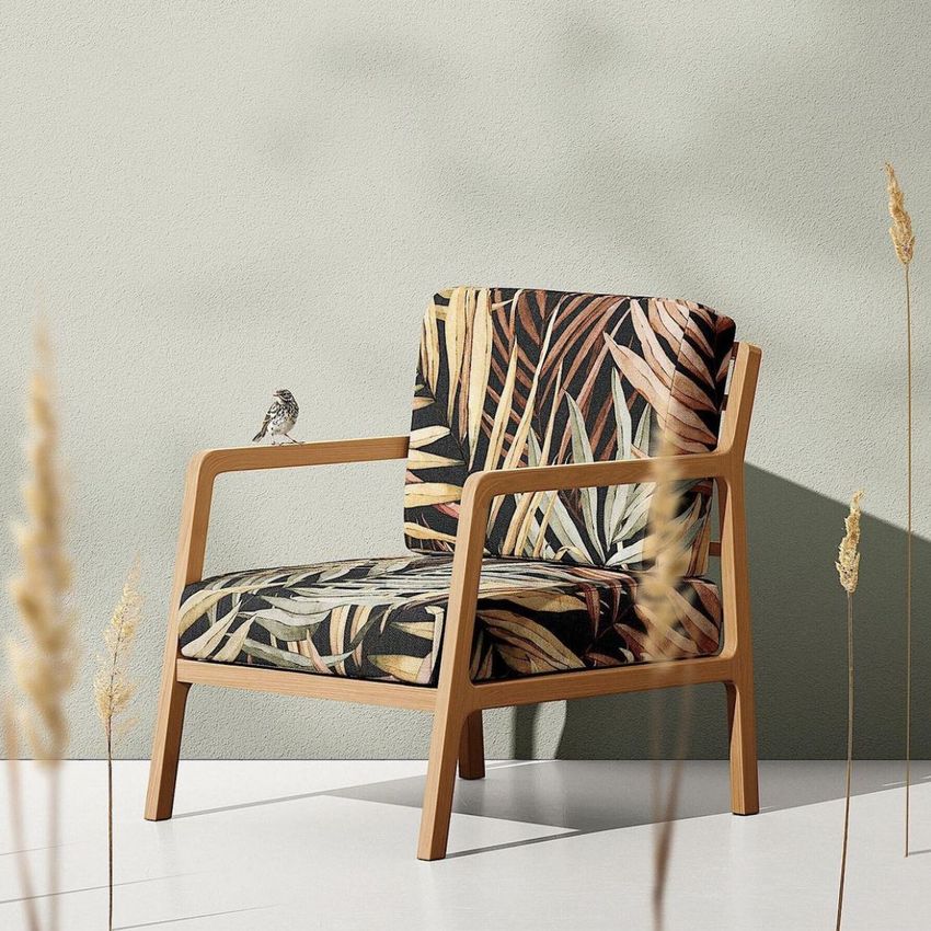 Lounge chair mockup with a wooden frame and patterned fabric upholstery featuring tropical leaves, set against a light textured wall.