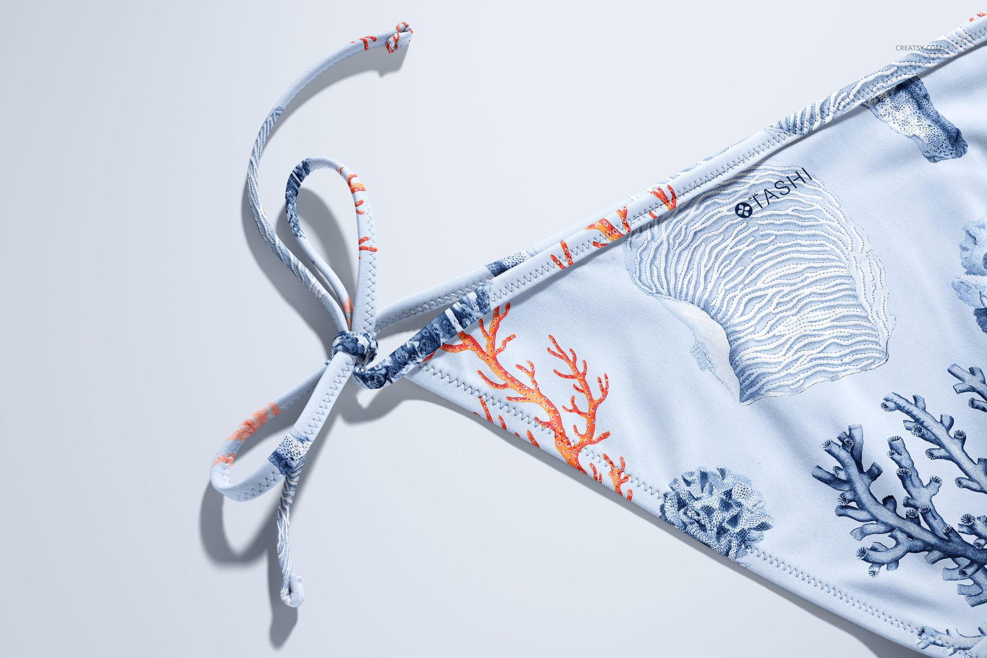 Close-up of bikini mockup featuring ocean-inspired coral and shell design in soft blue and orange hues.