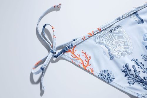 Close-up of bikini mockup featuring ocean-inspired coral and shell design in soft blue and orange hues.