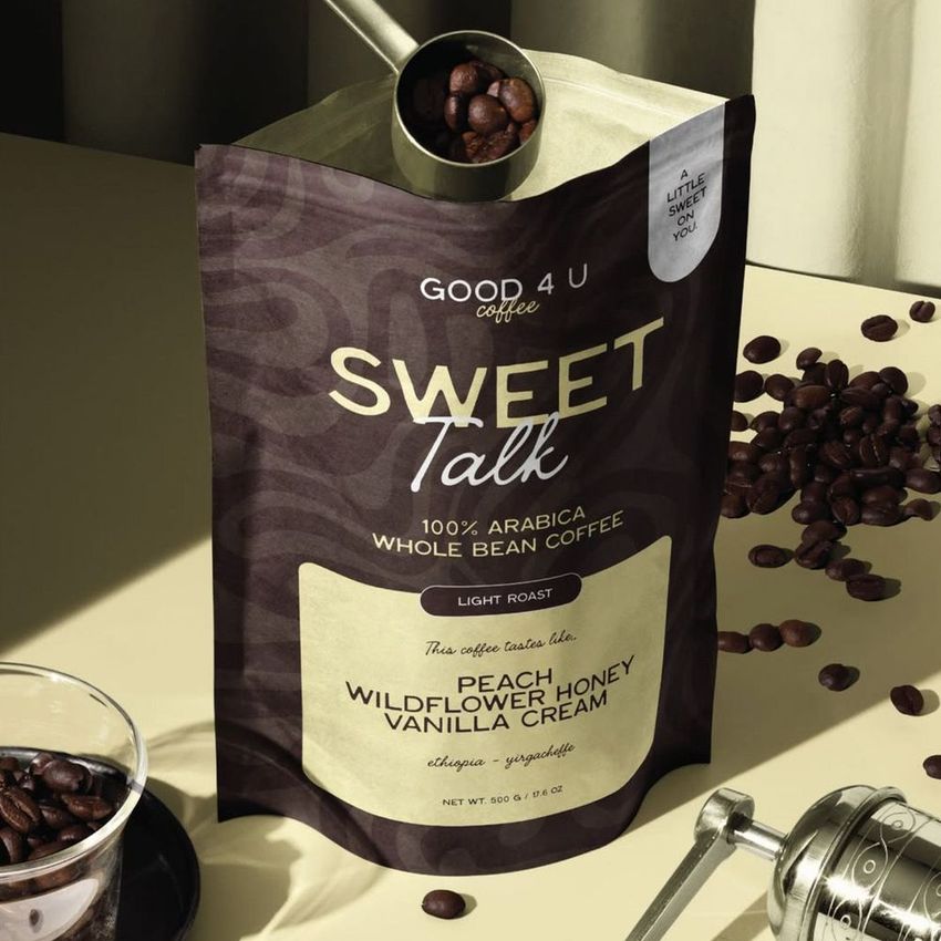 Coffee branding mockup featuring a brown and beige coffee bag with whole beans, metallic scoop, and a grinder on a neutral surface.