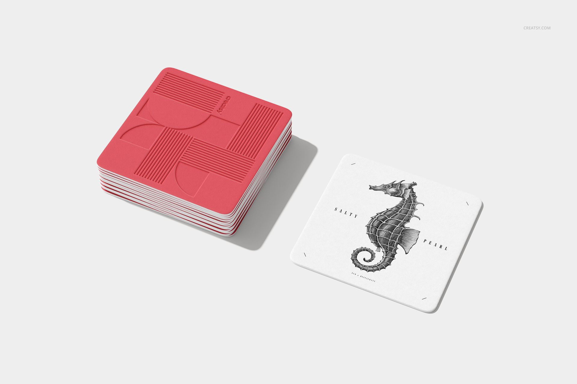 Square coaster PSD mockup set showing a pile of red patterned coasters and a white coaster with a seahorse drawing.