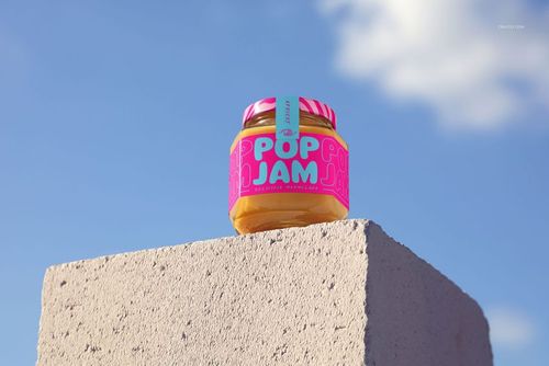Front view of a granadilla jam jar mockup featuring a vivid pink and blue label, set outdoors on a textured stone block.