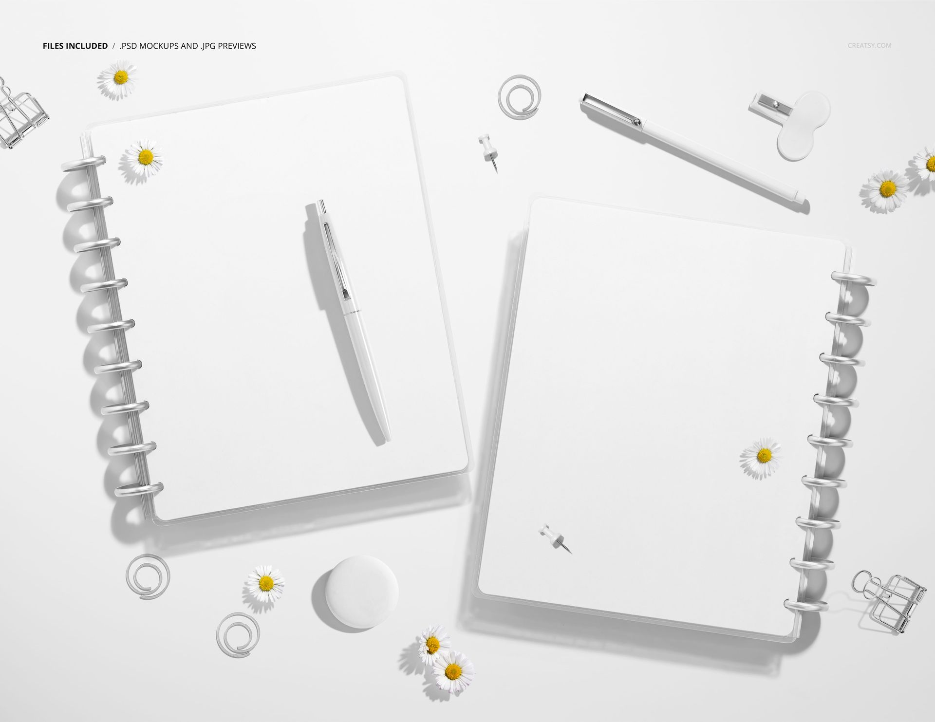 Spiral planner mockup showing front and back views of two white notebooks with pens and daisies on a light surface.