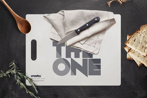 Rectangular polyethylene cutting board mockup with bold text design, knife and cloth on top, viewed from above.