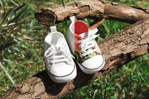 Baby sneakers mockup featuring two shoes on wood outdoors, one white and one with red and green patterned design.
