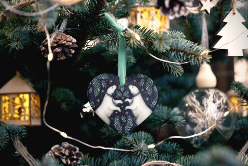 Heart-shaped Christmas ornament mockup featuring a dark patterned design with two white animals, hanging on a tree.