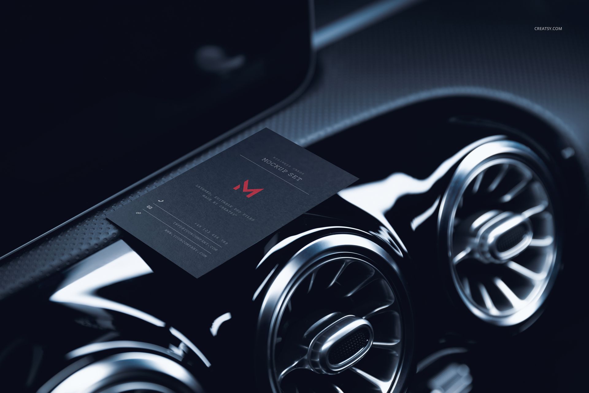 Black automotive business card mockup displayed on a car dashboard with metallic air vents in close-up view.