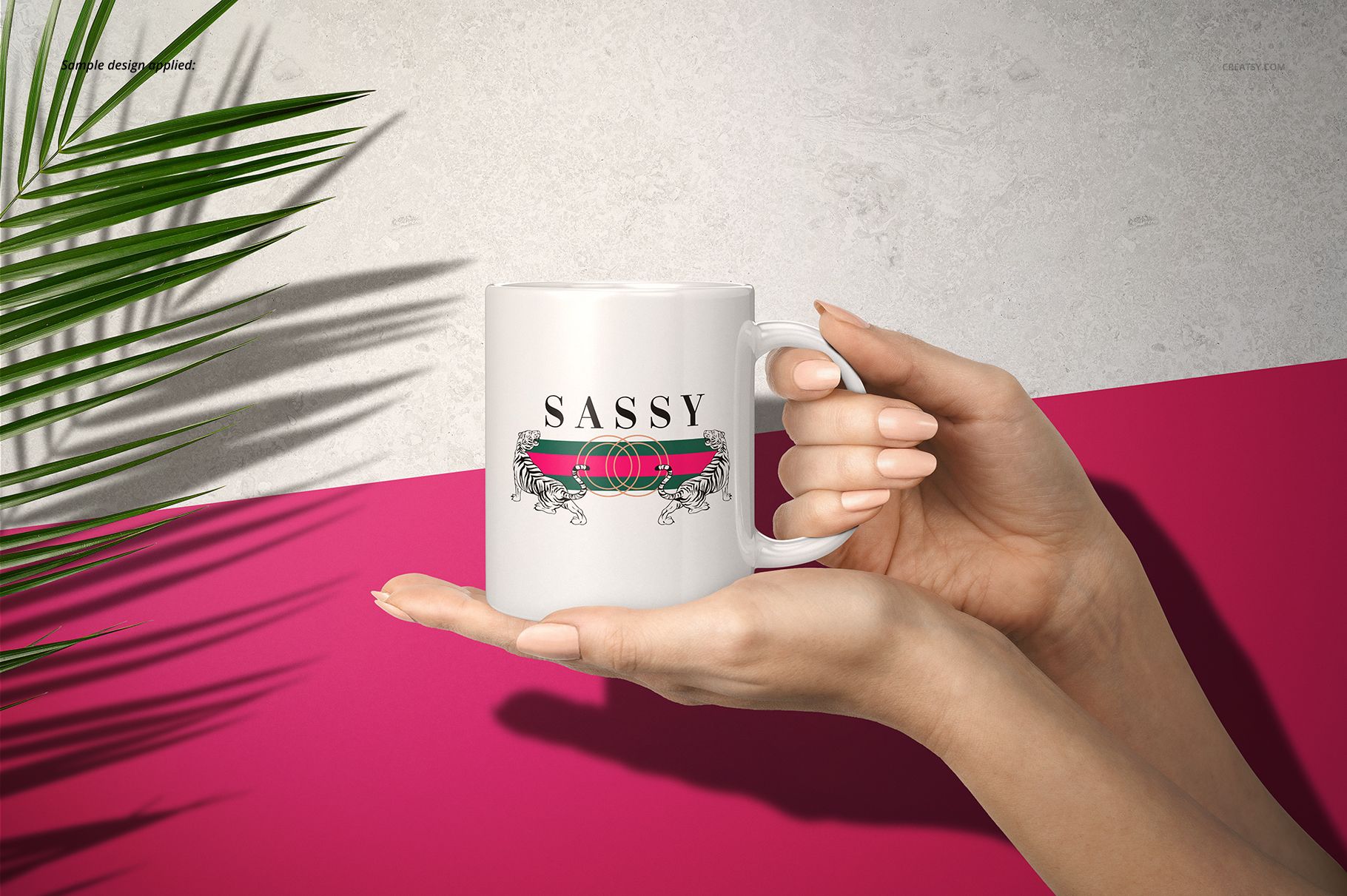 White 11oz mug with a bold pink and green stripe and 'SASSY' text, held by two hands against a pink and gray background.
