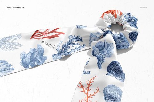 Fashion accessory mockup displaying a scrunchie scarf with ocean-inspired blue and red coral designs on white.